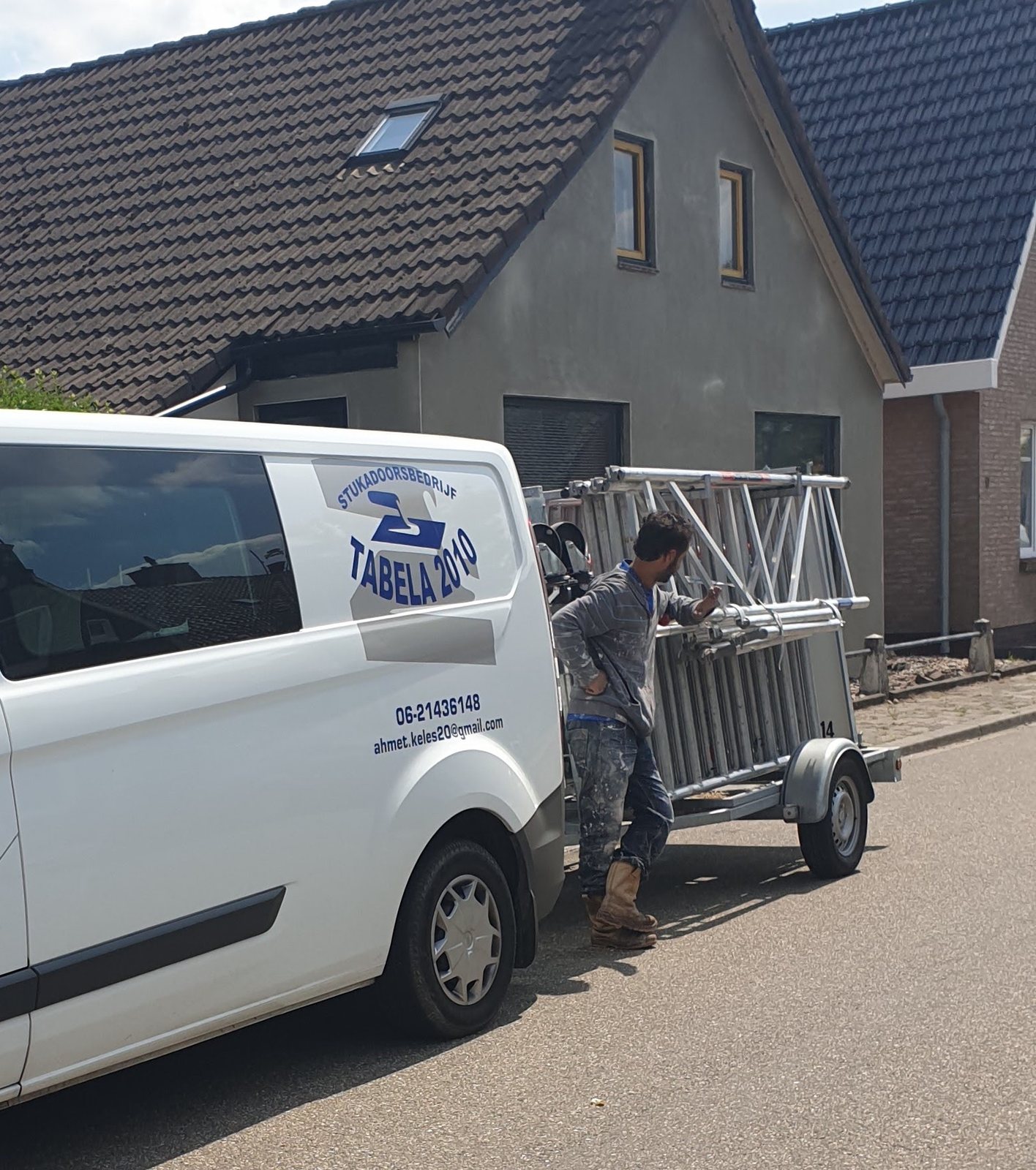Witte bedrijfsbus van Stukadoorsbedrijf Tabela met een stukadoor bij een steigeraanhanger