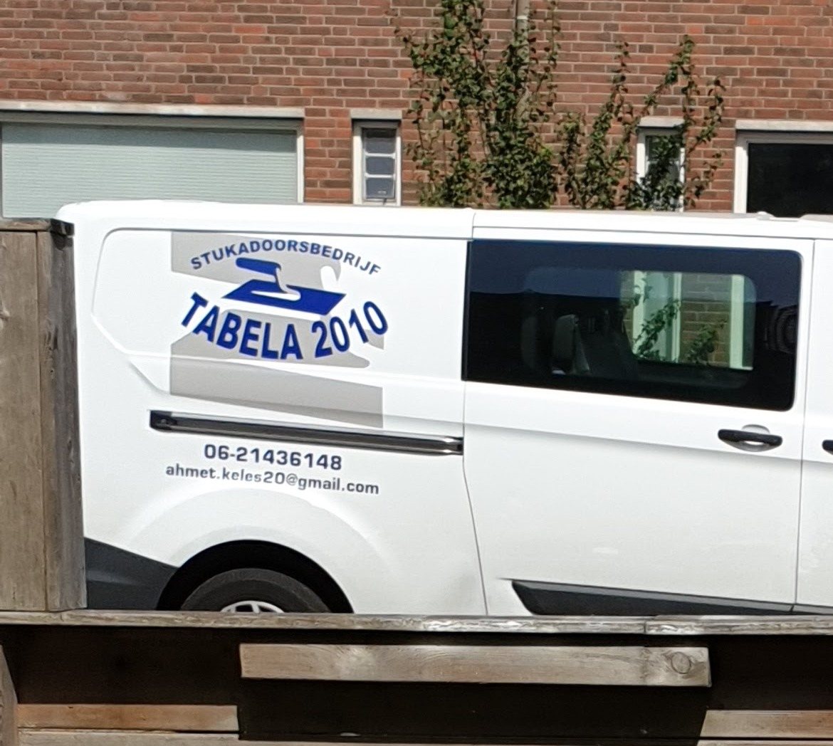 Zijkant van de bus met het logo Stukadoorsbedrijf Tabela 2010, telefoonnummer en e-mailadres