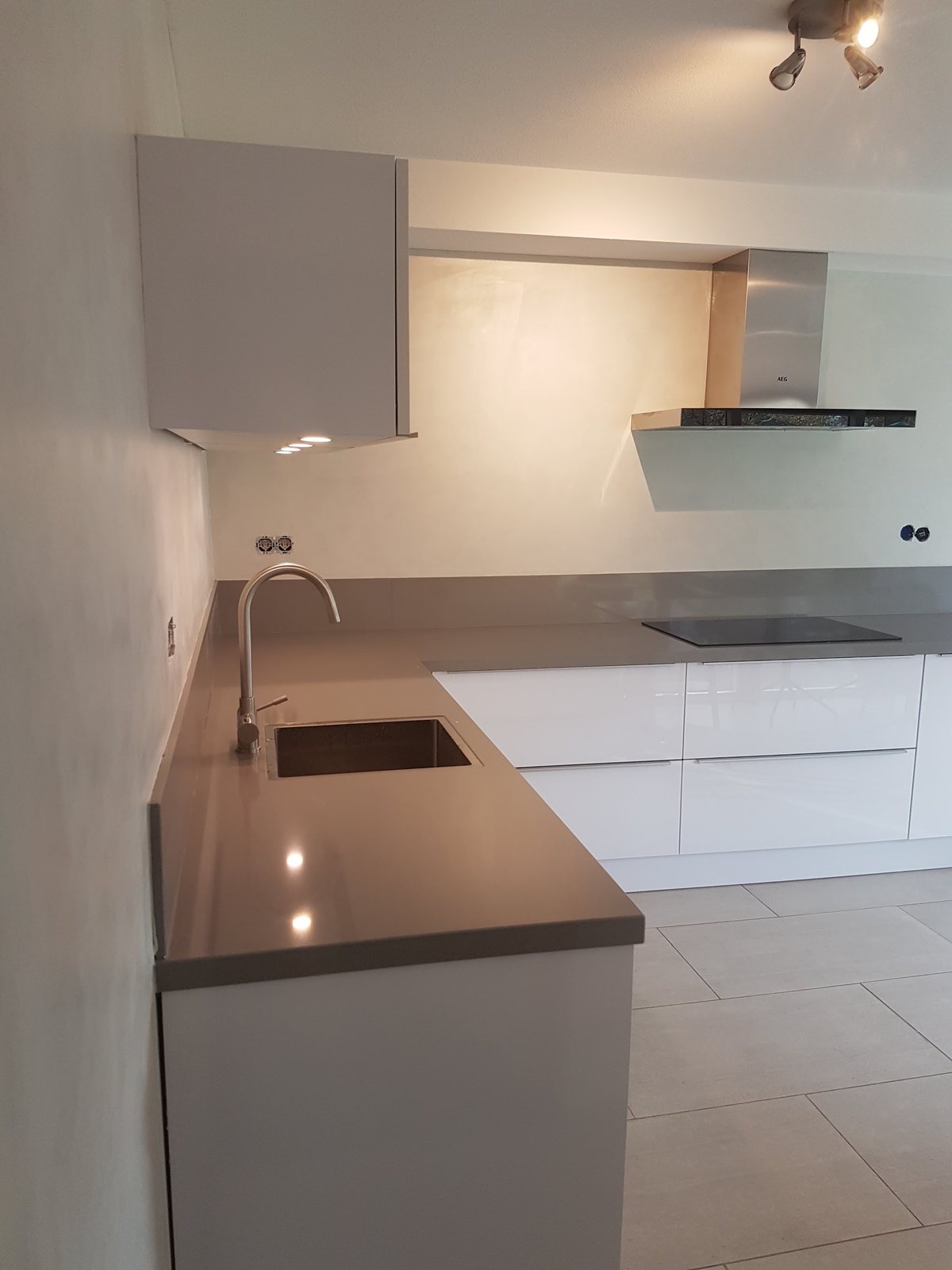 Nieuwe keuken met grijs werkblad en strakke lichte wanden